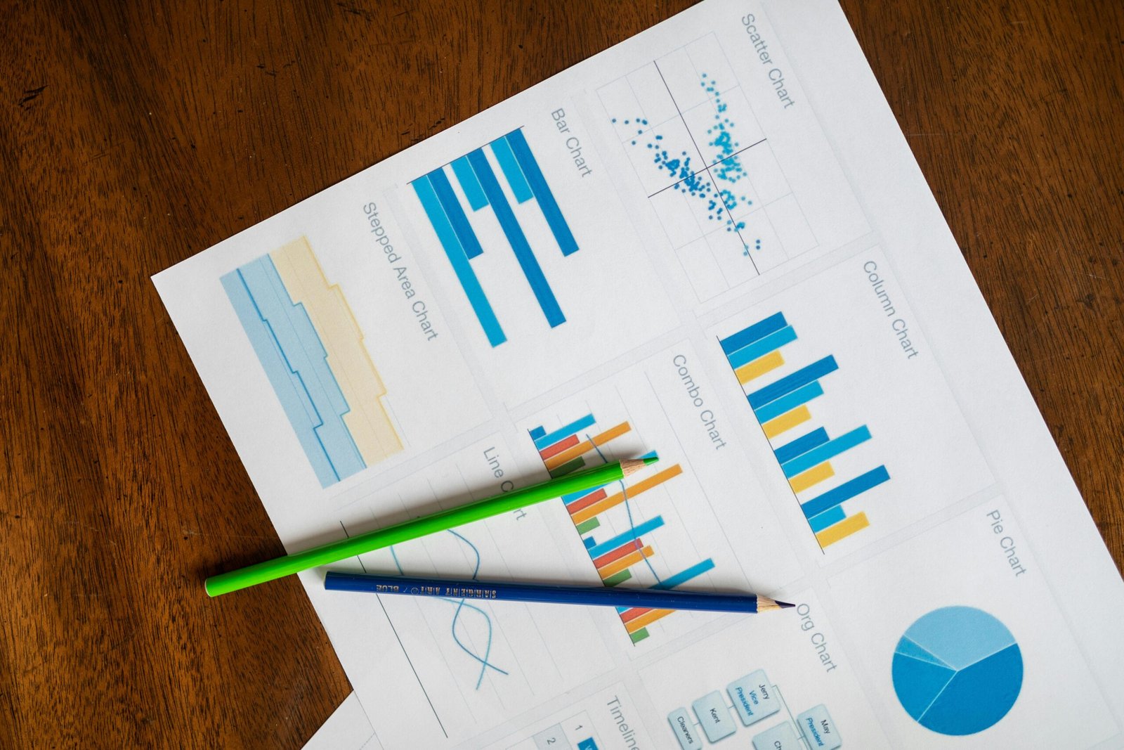 Top view of vibrant charts and colored pencils on wooden surface.